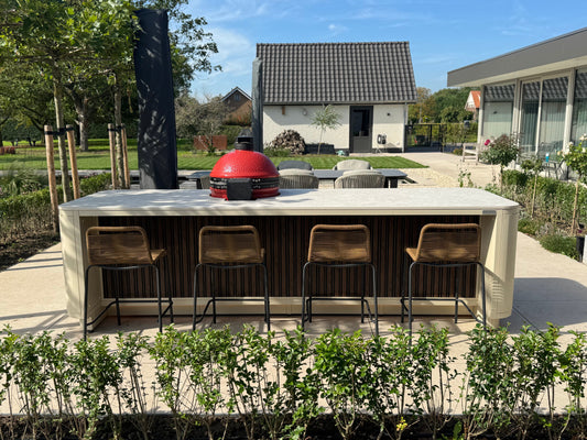 Luxe buitenkeuken met bar en loungehoek in groene setting